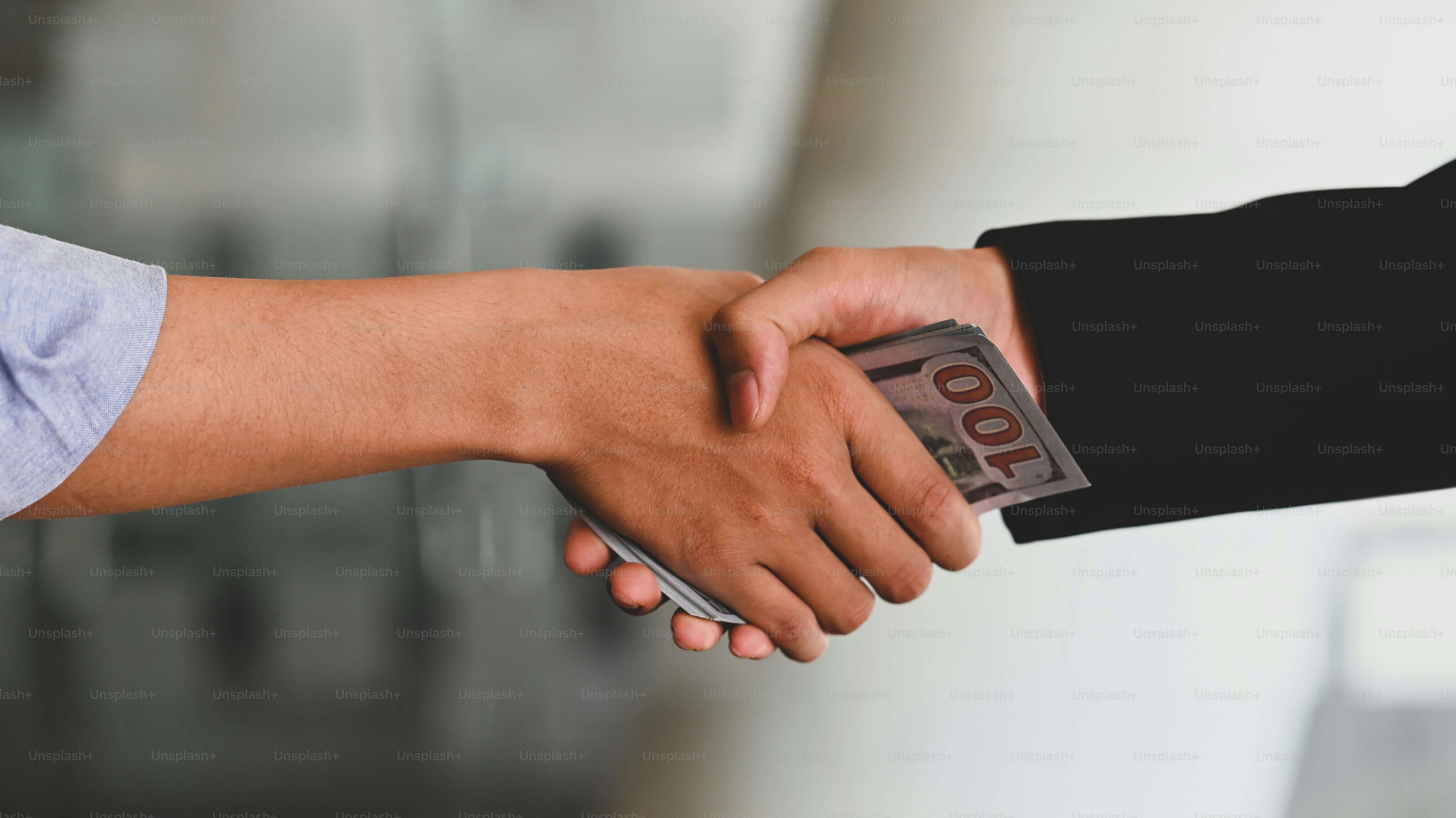 Cropped shot of Businessmen shaking hands after finished meeting or negotiation with the blurred office as background. Partnership/Dealing/Corruption concept.